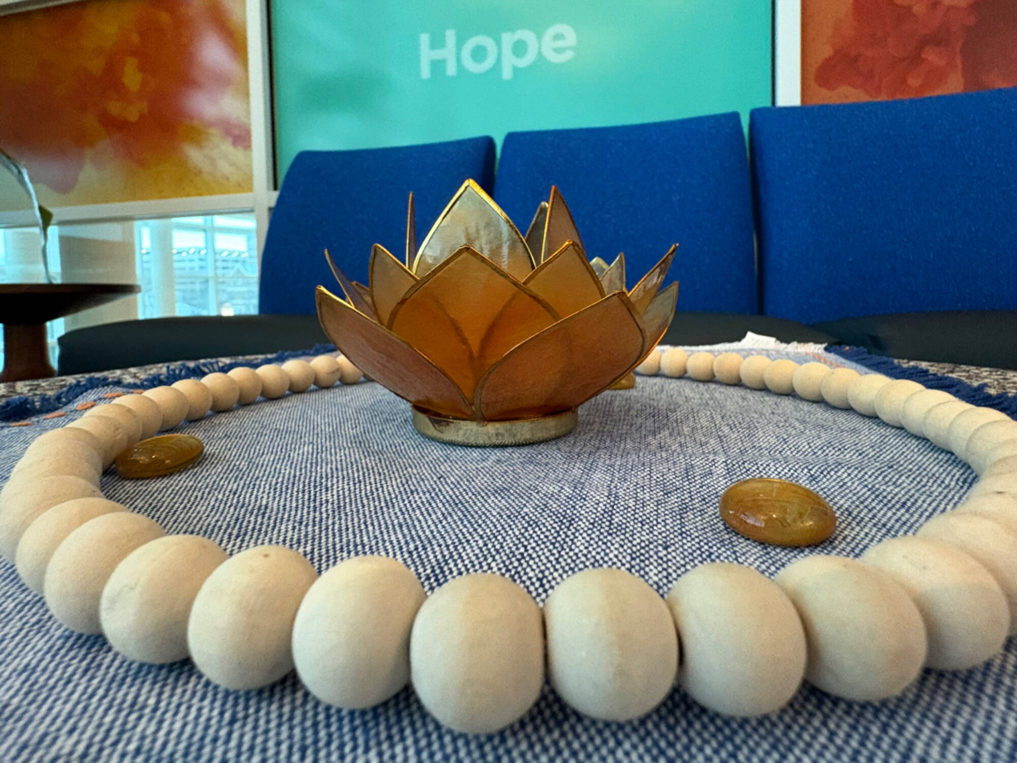 A close-up of a lotus-shaped candle holder surrounded by a circle of wooden beads.